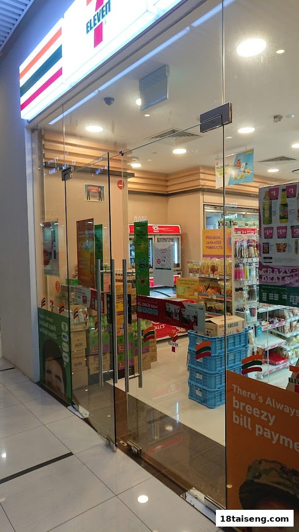 The glass entrance of a 7-Eleven convenience store, showcasing its interior products and services.