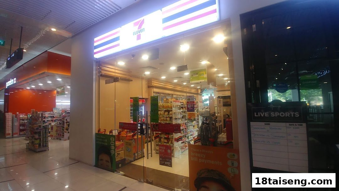 The brightly lit storefront of a 7-Eleven convenience store, showcasing its wide glass entrance.
