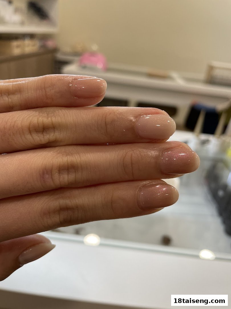 A close-up of a hand displaying freshly manicured nails with a natural, glossy finish.