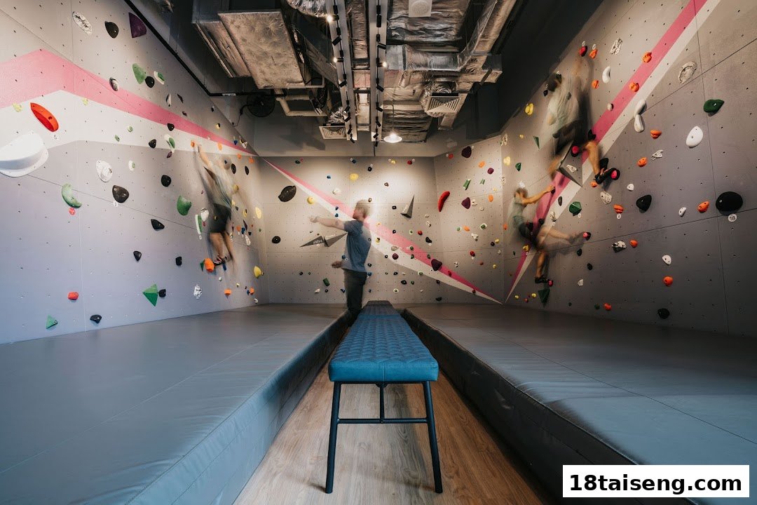 People engage in bouldering on a vibrant climbing wall with various holds and safety mats.