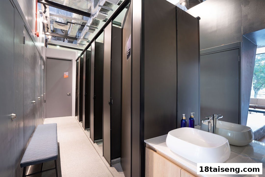 A modern and clean changing room area with lockers, private stalls, and vanity sinks.