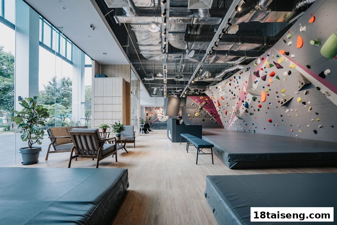 A spacious indoor bouldering gym featuring colorful climbing walls, safety mats, and a comfortable lounge area.
