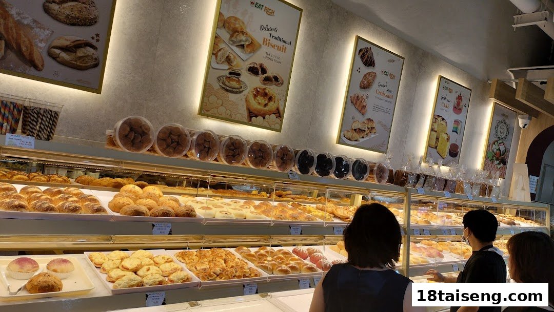 Brightly lit bakery interior showcasing a wide array of fresh pastries and breads, with customers browsing.