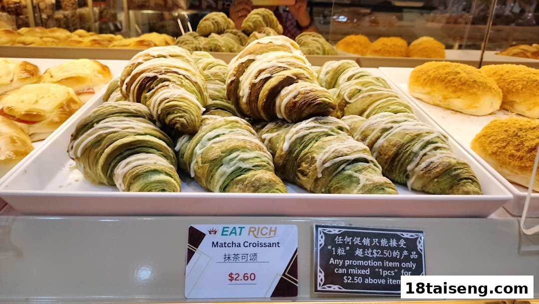 A vibrant display of green matcha croissants and other freshly baked pastries in a glass case at Eat Rich.