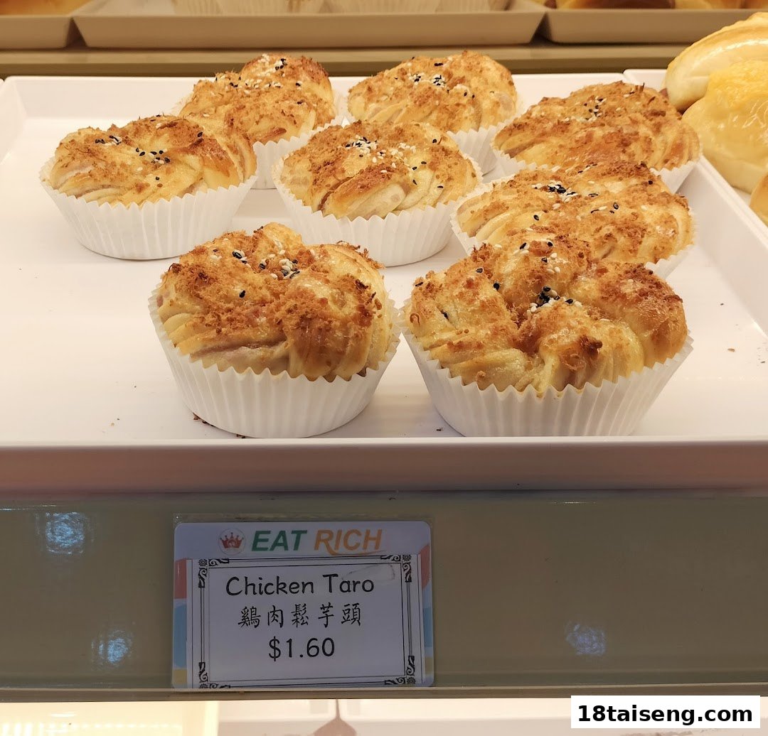 A tray of golden-brown Chicken Taro buns displayed with a price tag from Eat Rich bakery.