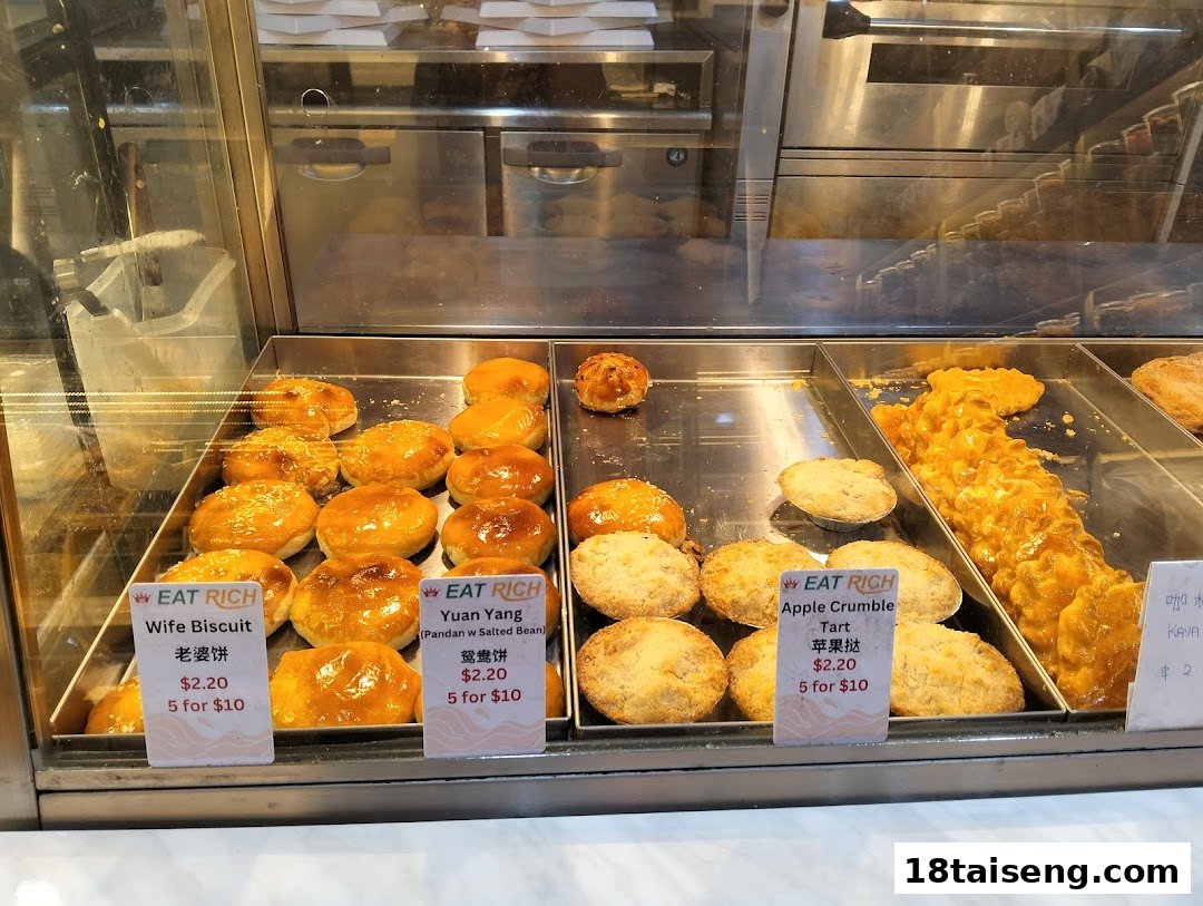 A vibrant display of freshly baked pastries and tarts with individual price labels at Eat Rich.