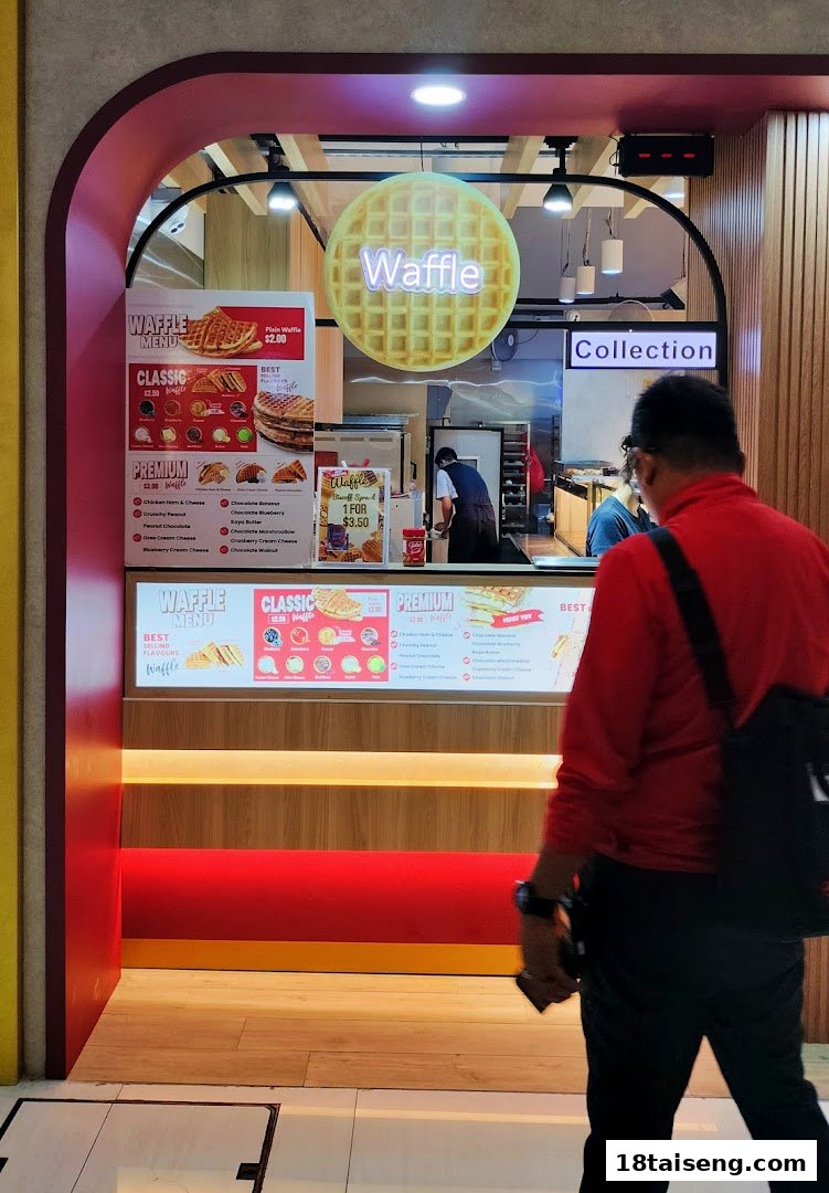 A vibrant red and wood-accented waffle shop front with visible menus and a customer walking by.