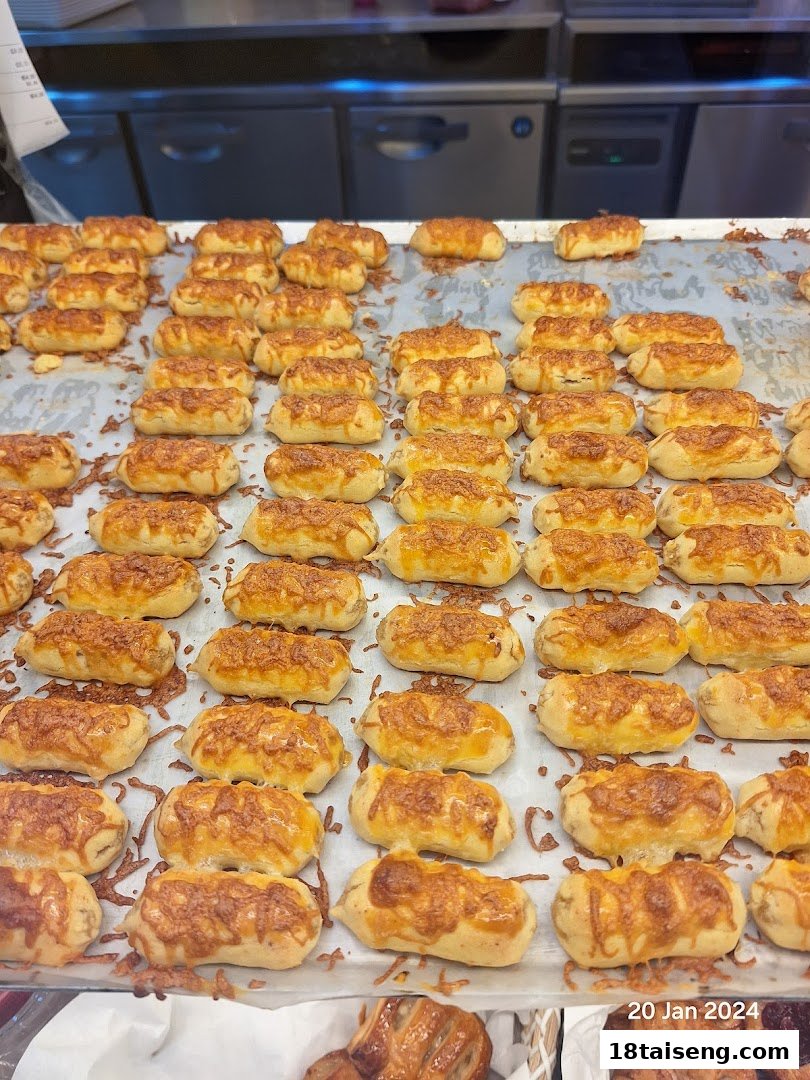 A large tray filled with numerous golden-brown baked goods, possibly cheese buns or savory pastries, ready for sale.