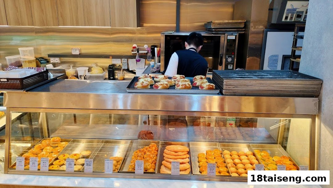 An interior shot of Eat Rich bakery, featuring a display case filled with various pastries and a staff member preparing items.