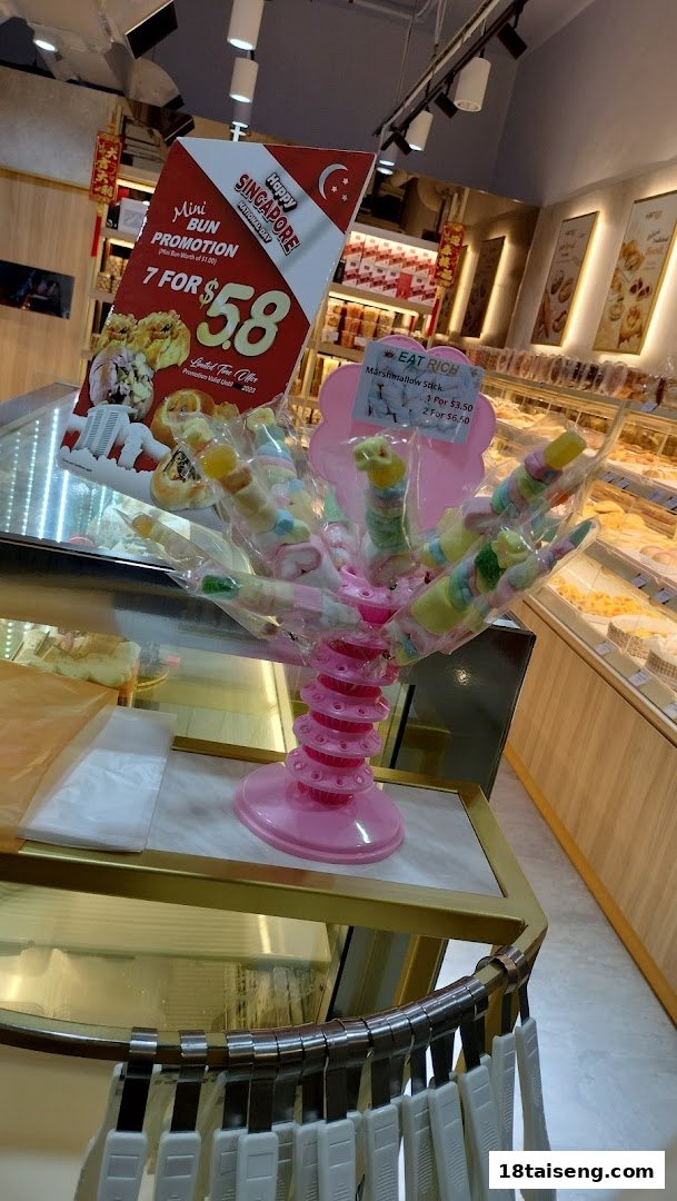 An interior shot of Eat Rich bakery, featuring a marshmallow stick display and a mini bun promotion sign.