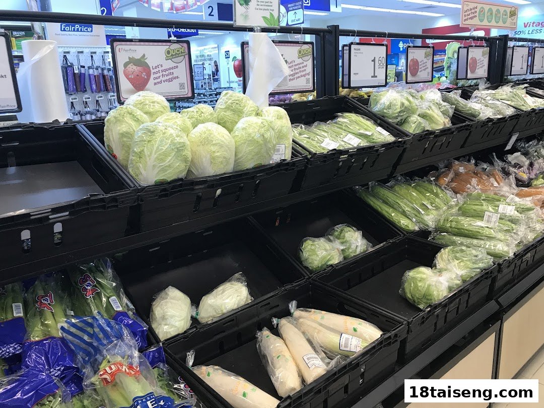 A vibrant display of fresh vegetables, including cabbage and leafy greens, in a supermarket produce section.