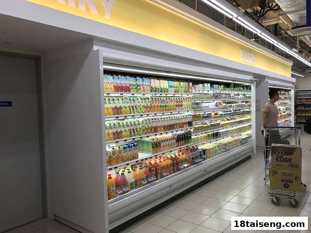 A brightly lit supermarket aisle featuring a wide selection of chilled dairy and juice products.