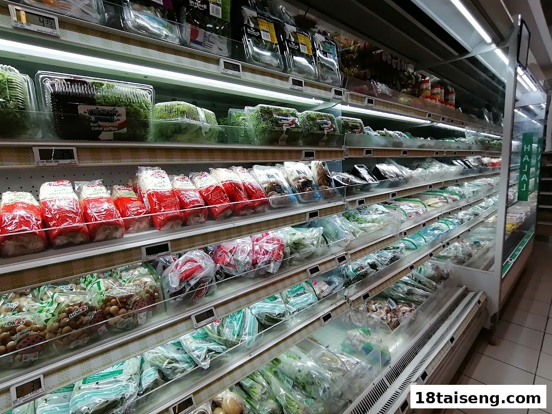 A well-stocked refrigerated aisle at FairPrice Tai Seng, featuring fresh produce, packaged vegetables, and mushrooms.