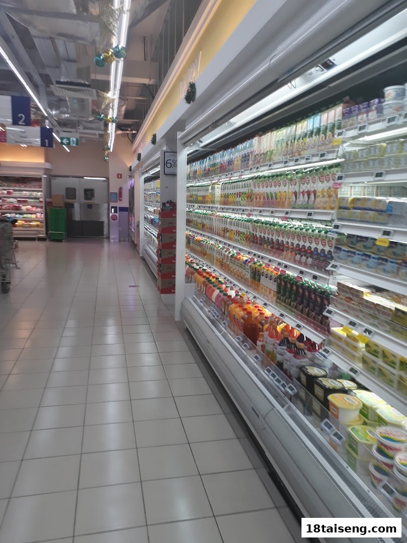 A brightly lit supermarket aisle showcasing a wide selection of refrigerated drinks and dairy products.