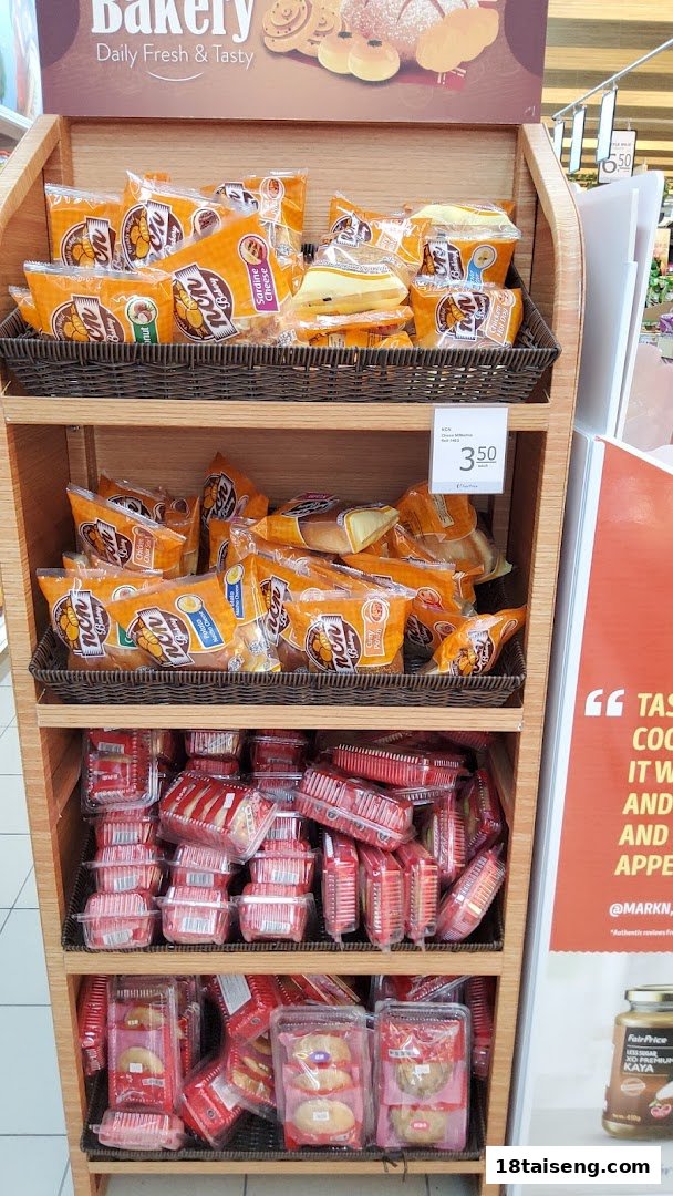 A wooden display stand at FairPrice Tai Seng showcasing a variety of packaged bakery items and pastries.