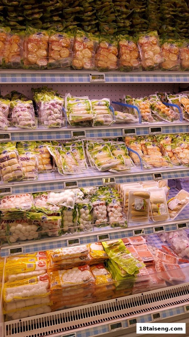 A refrigerated display shelf at FairPrice Tai Seng, stocked with various packaged fish balls and processed seafood items.
