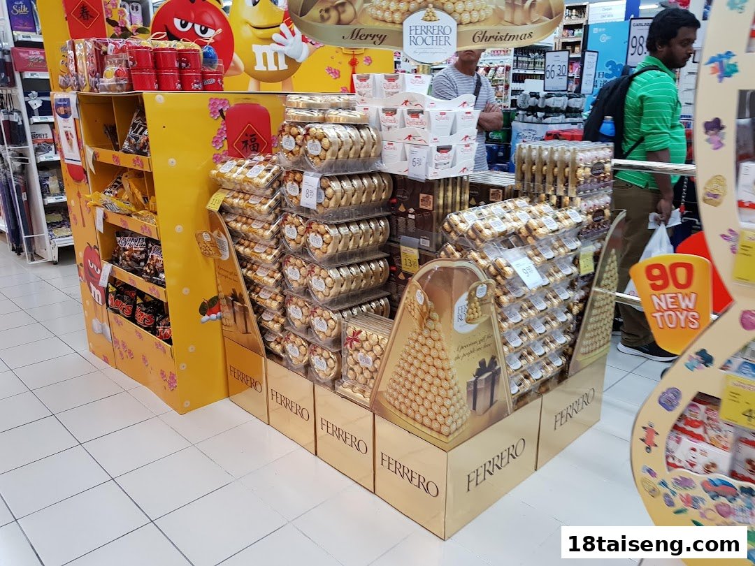 A supermarket aisle featuring large displays of Ferrero Rocher chocolates and M&M's candies.