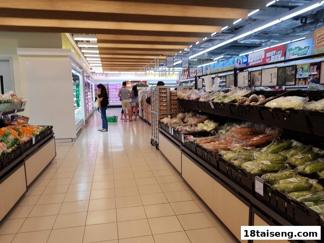An interior view of FairPrice Tai Seng supermarket, showcasing fresh produce aisles and shoppers.