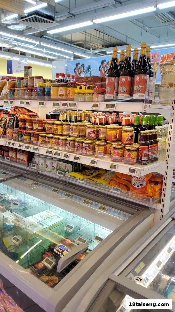An aisle in FairPrice Tai Seng supermarket, featuring shelves stocked with various condiments and freezer chests.