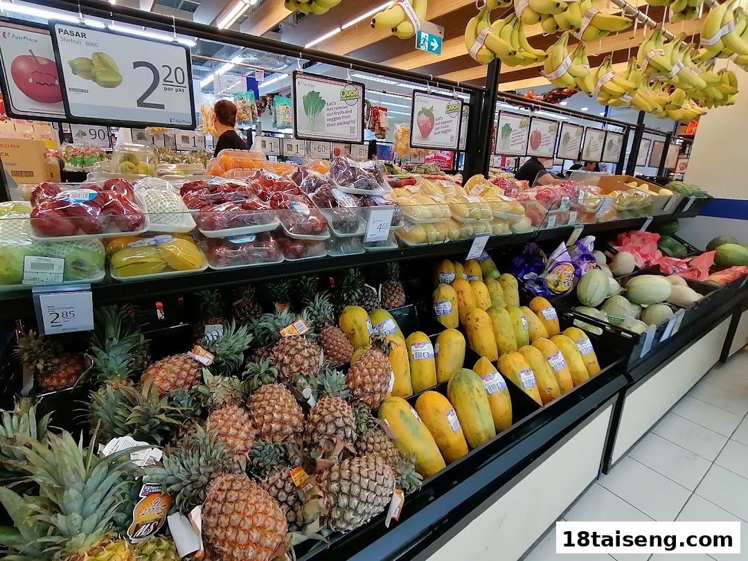 A vibrant display of fresh fruits and vegetables, including pineapples, papayas, and packaged produce, in a supermarket aisle.