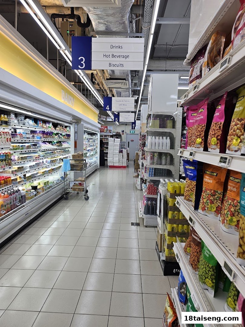 An aisle in FairPrice Tai Seng supermarket, featuring refrigerated dairy products and shelves stocked with snacks.