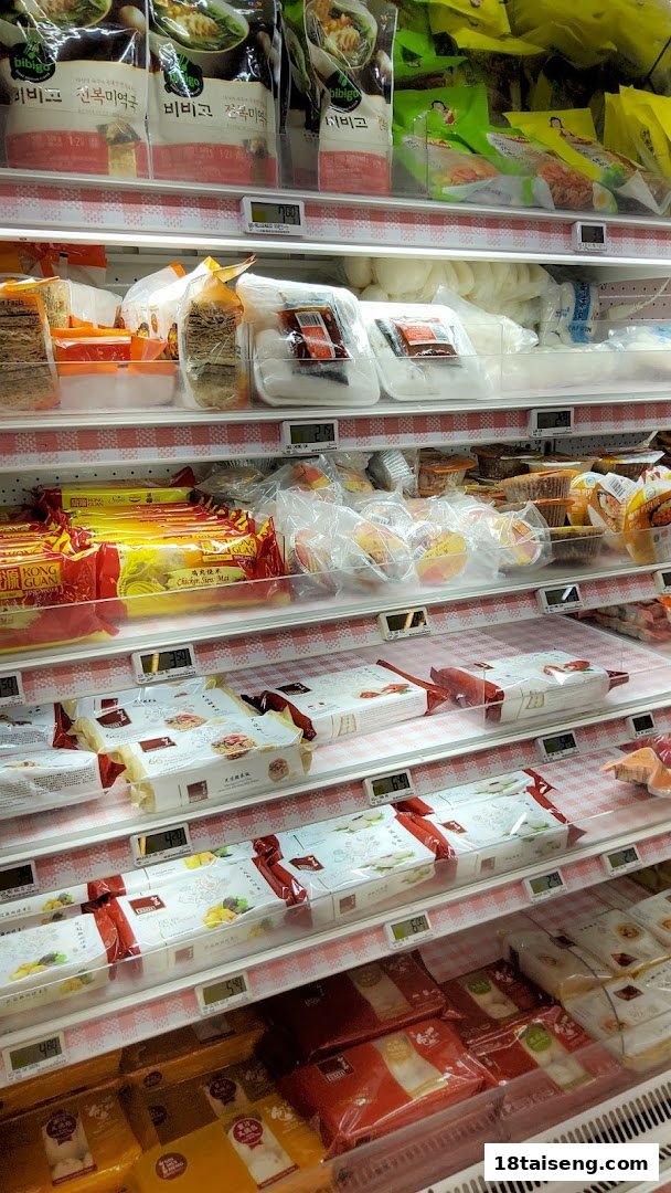 A well-stocked refrigerated aisle in a supermarket, featuring various packaged food items and digital price tags.