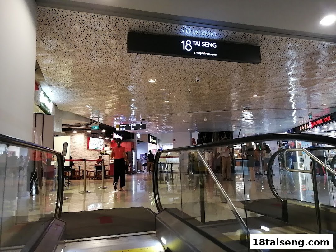 A view from an escalator looking down into a bright, bustling mall dining area.