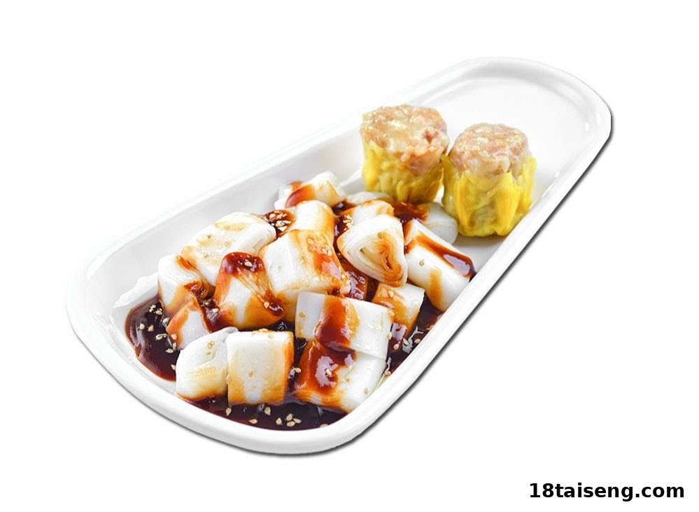 A white rectangular plate holds rice rolls drizzled with sauce and sesame seeds, alongside two steamed siew mai.