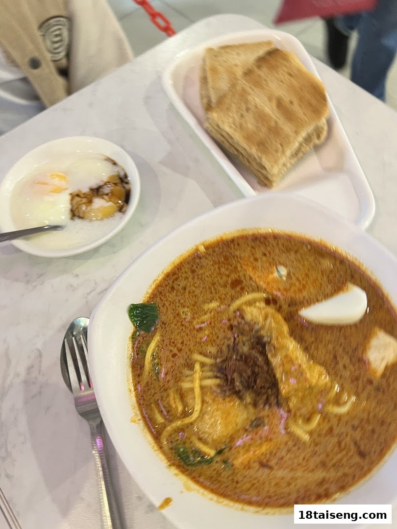 A table with a bowl of curry noodles, soft-boiled eggs, and toast, showcasing a typical meal.