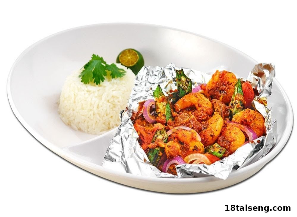 A vibrant dish featuring spicy prawns, okra, and red onions served with white rice and a lime wedge.
