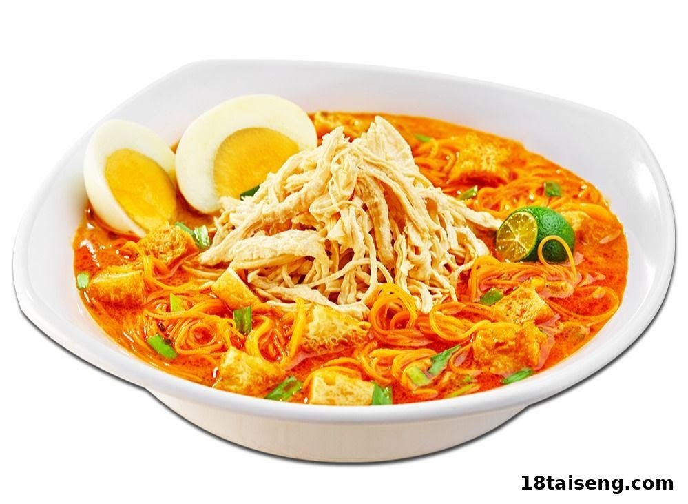 A vibrant bowl of curry noodles topped with shredded chicken, a hard-boiled egg, and a lime wedge.