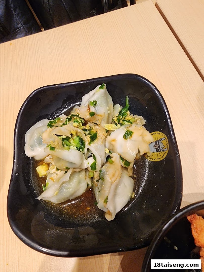 A close-up of a black bowl filled with delicious dumplings, garnished with green onions and egg.