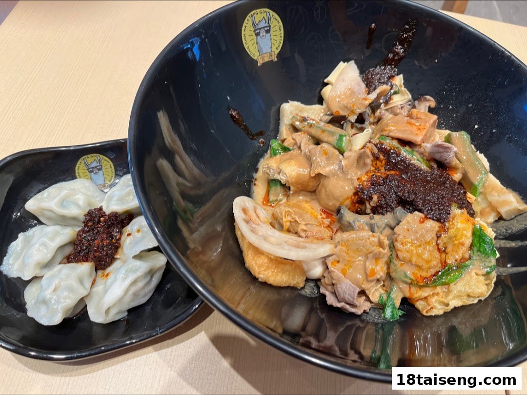 A large bowl of spicy mala tang with various ingredients and a side of dumplings with chili oil.