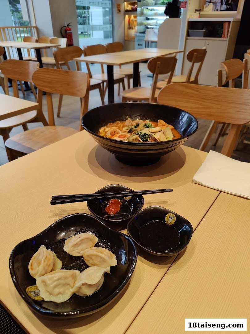A delicious bowl of mala tang and dumplings served on a table in a modern, inviting restaurant interior.