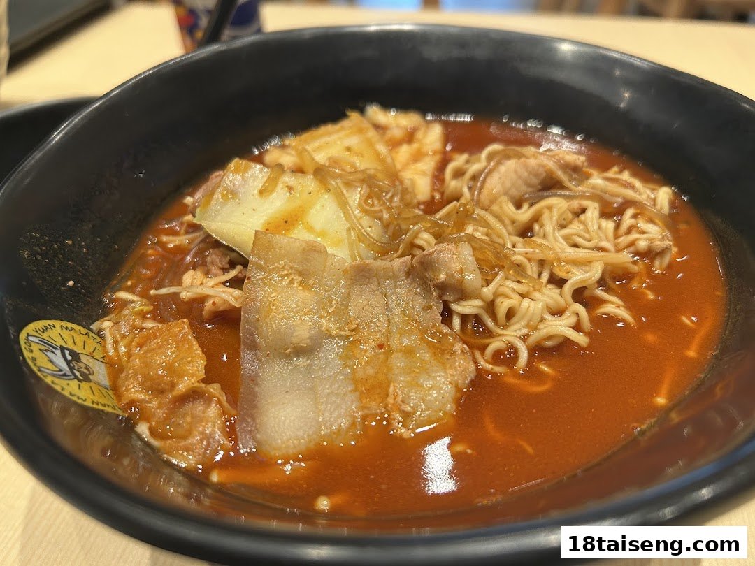 A close-up of a vibrant bowl of Mala Tang with noodles, pork belly, and various ingredients in a spicy broth.