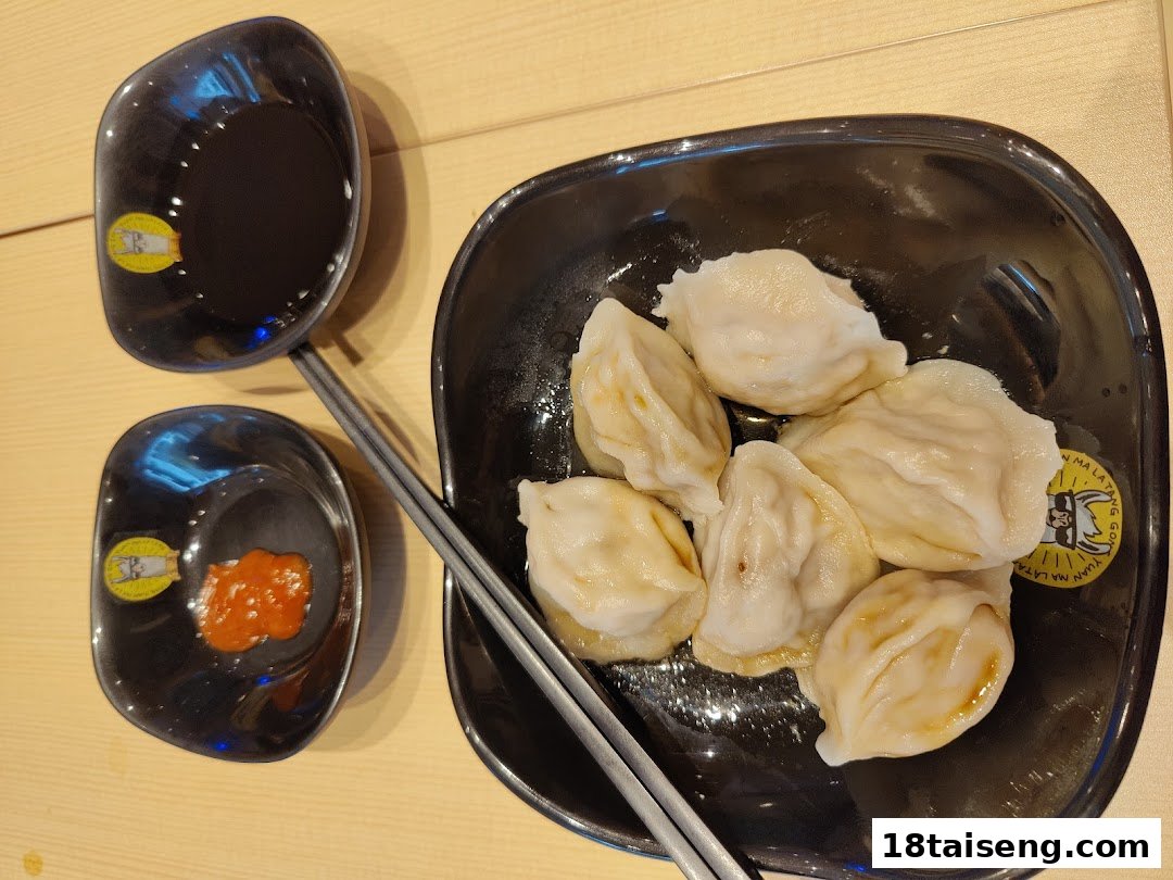 A plate of delicious dumplings served with soy sauce and chili sauce, ready to be enjoyed.