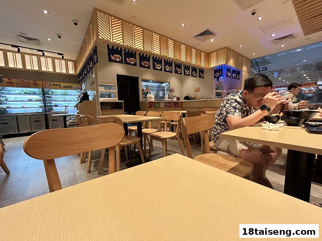 Interior view of Gong Yuan Ma La Tang, showing customers dining and a fresh ingredient display.