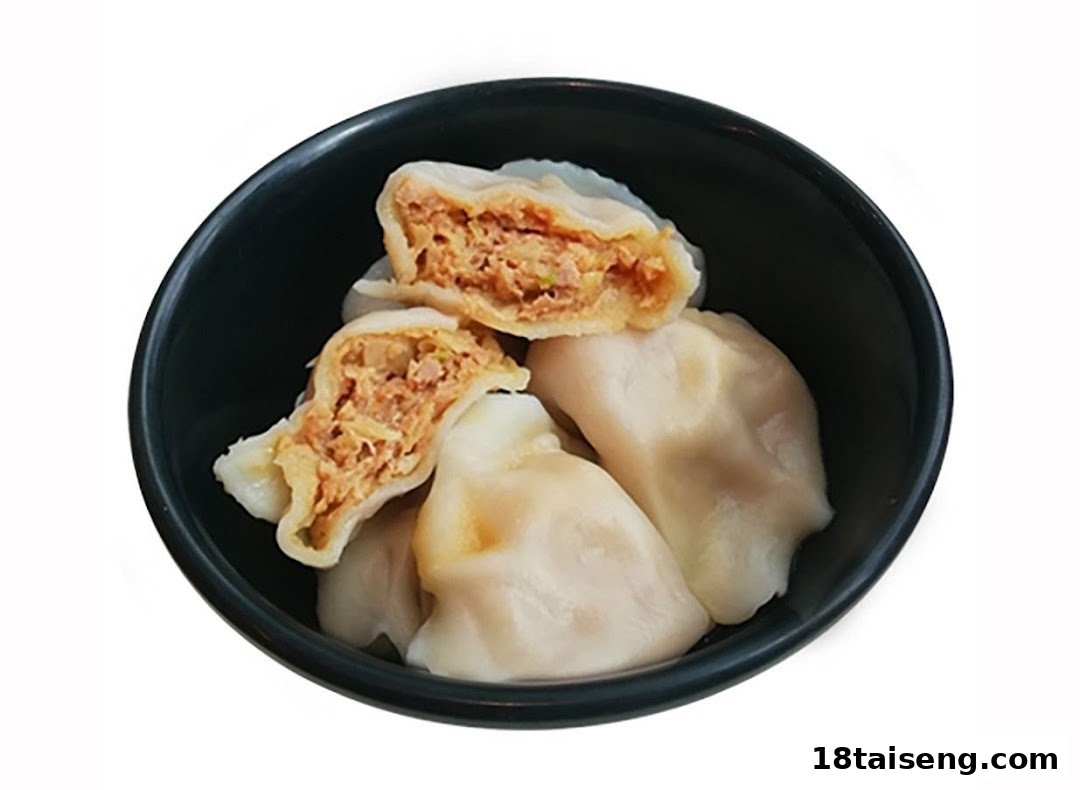 A bowl of freshly steamed dumplings, with one cut open revealing the savory filling.