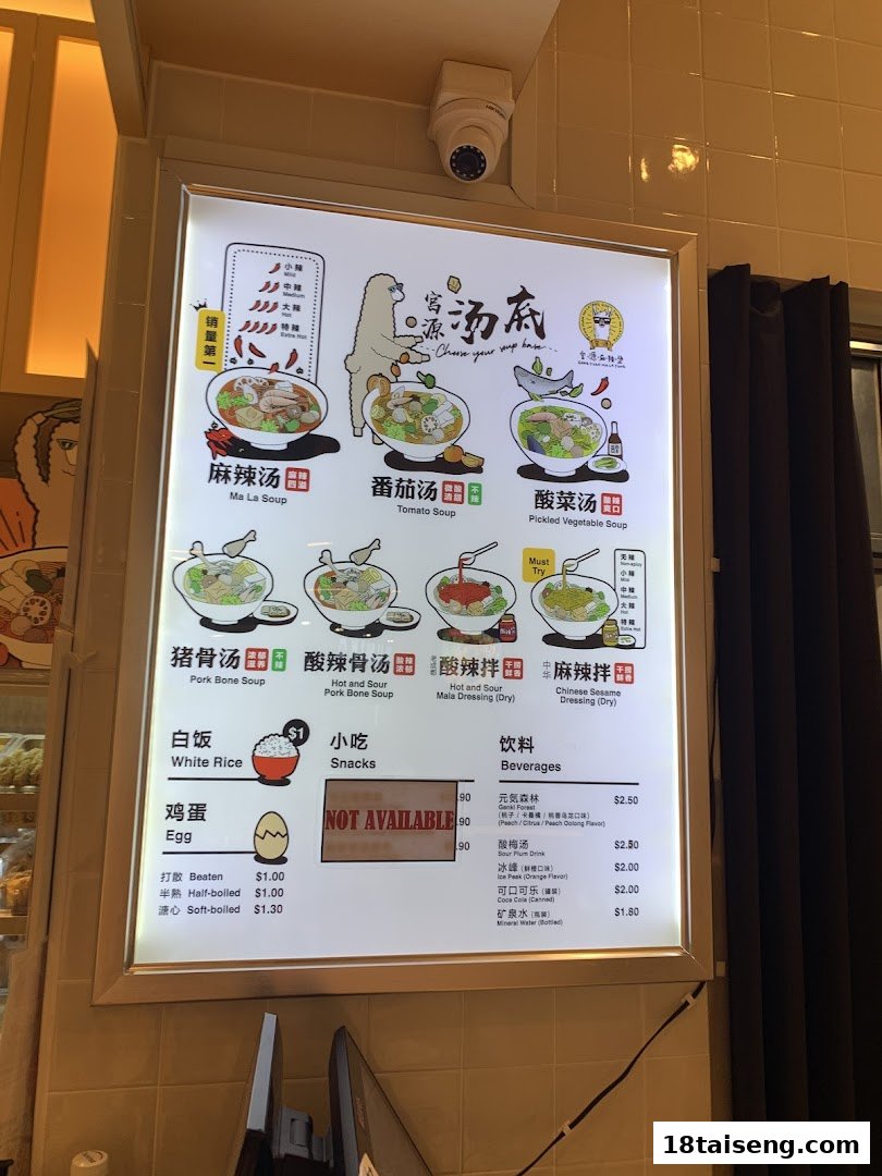 A brightly lit menu board displaying various soup bases, sides, and beverages at Gong Yuan Ma La Tang.
