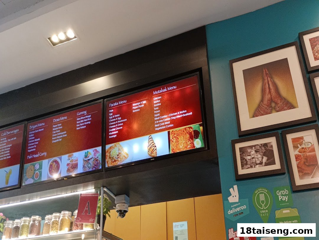 Digital menu boards displaying a variety of Indian and local dishes inside Jalan Kayu The Prata Cafe.