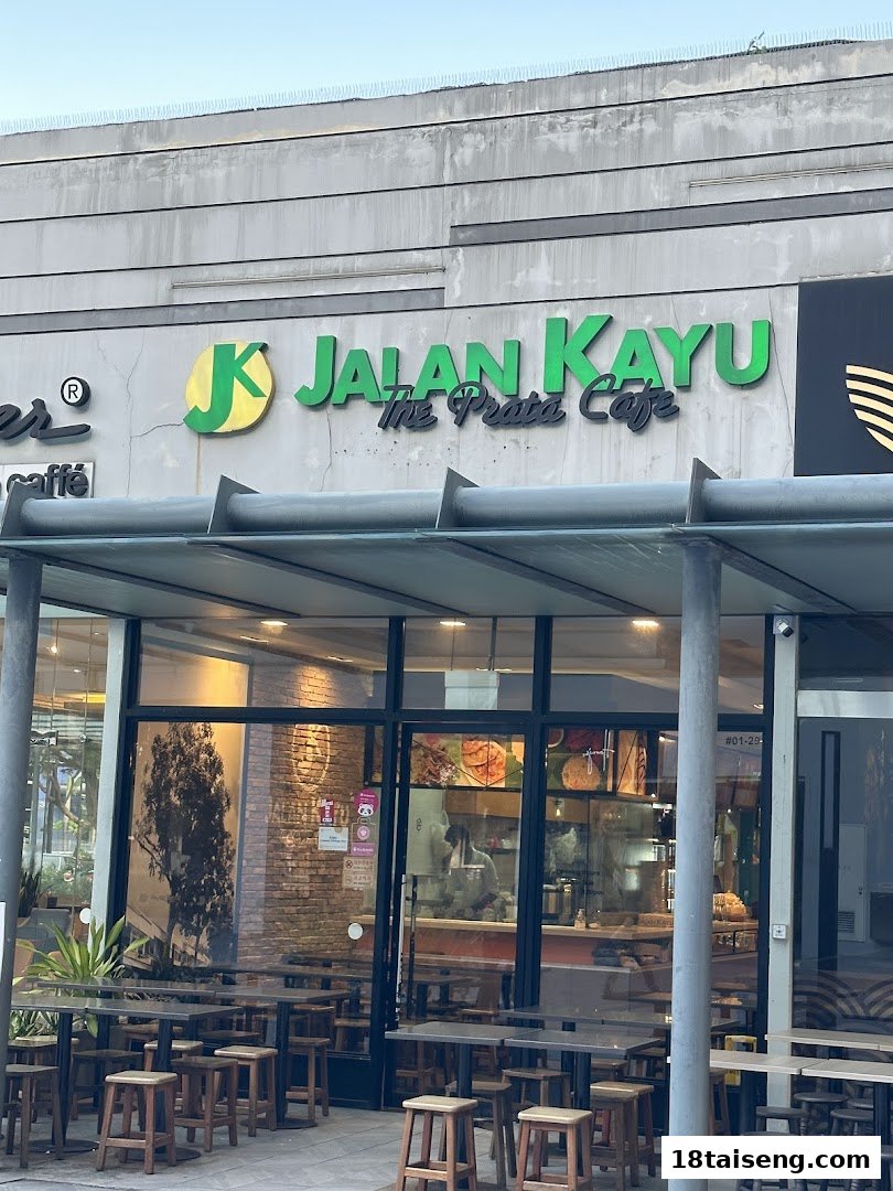 Exterior view of Jalan Kayu The Prata Cafe, featuring its green signage and outdoor seating area.