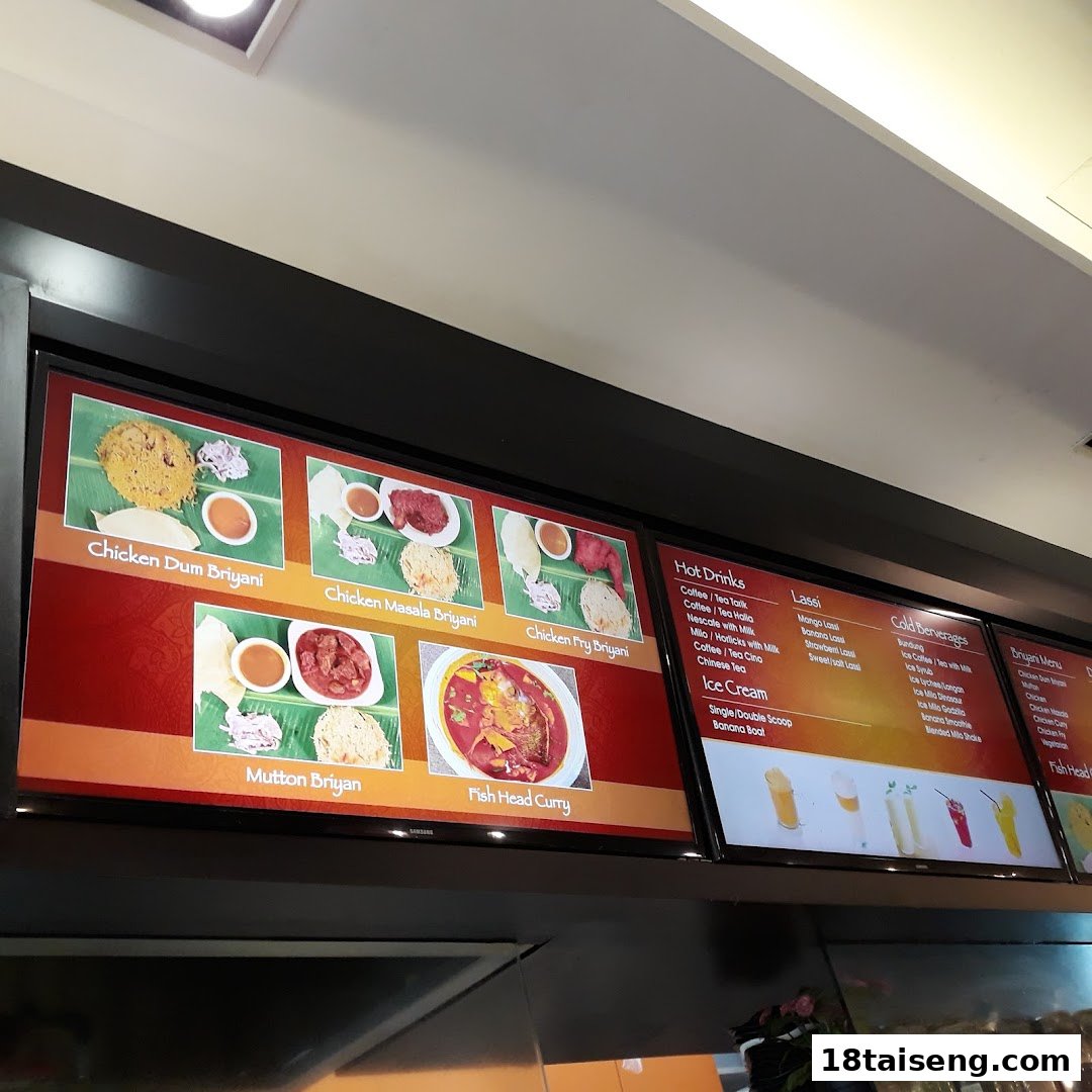 Digital menu boards displaying a variety of Indian biryani dishes, curries, and beverages.