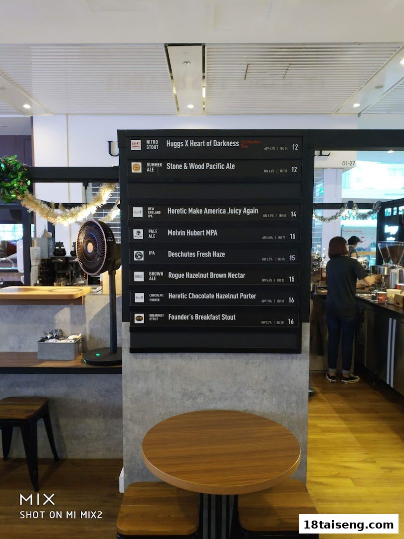 Interior shot of a cafe featuring a prominent craft beer menu board and seating area.