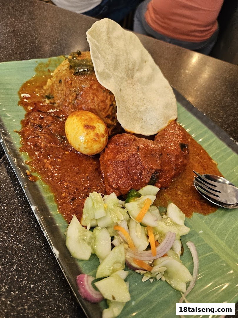 A vibrant plate of Indian curry with rice, chicken, egg, papadum, and fresh cucumber salad.