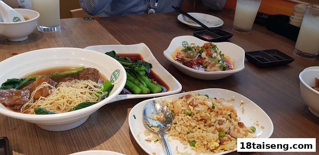 A table filled with various Asian dishes, including beef noodles, stir-fried vegetables, dumplings, and fried rice.