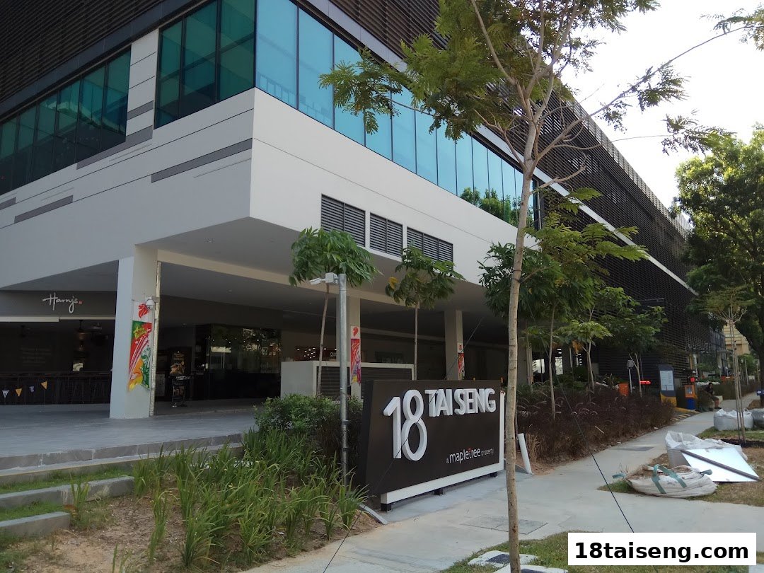 Exterior view of a modern commercial building with a shop entrance and surrounding greenery.