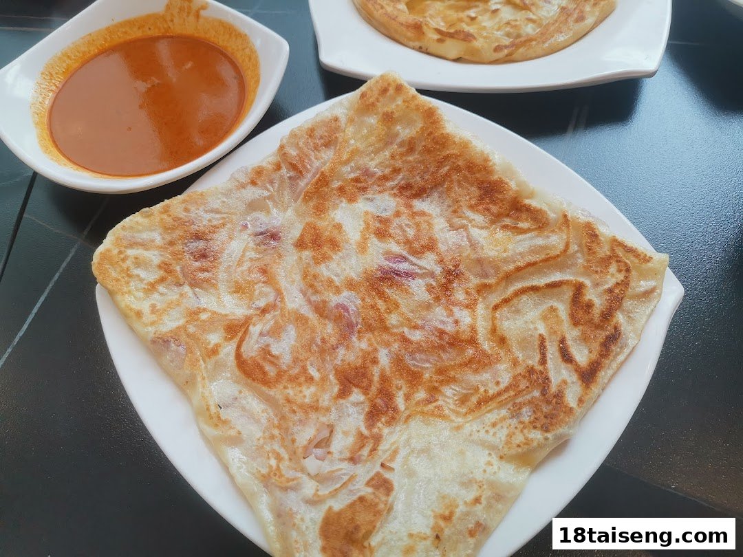 A close-up of a crispy prata served with a side of rich curry sauce.