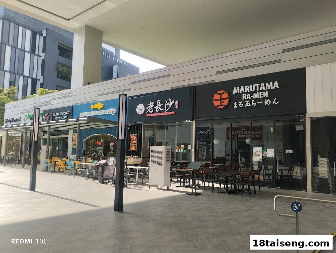 A row of diverse restaurant shopfronts with outdoor seating under a covered walkway.