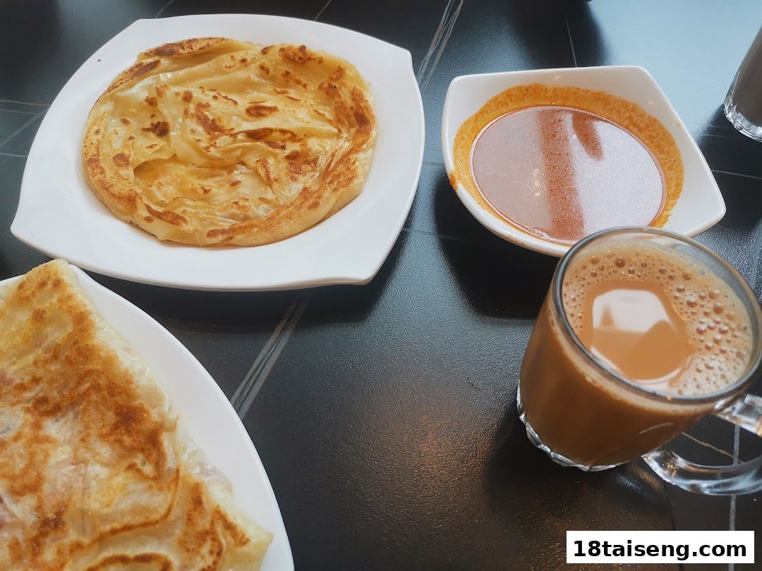 Delicious prata, curry, and a hot beverage served on a dark table at Jalan Kayu The Prata Cafe.