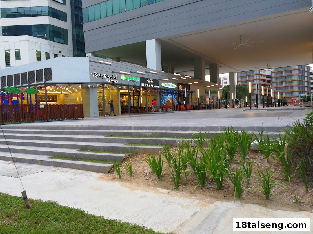 Exterior view of a modern commercial building featuring multiple dining establishments and an outdoor play area.